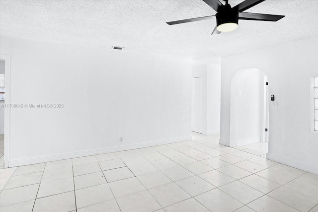 spare room featuring a ceiling fan, arched walkways, visible vents, and a textured ceiling