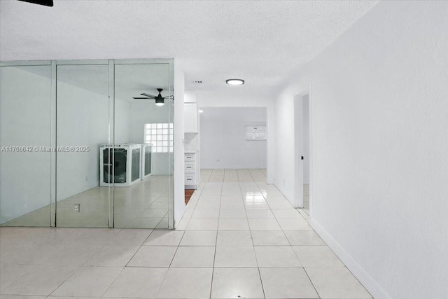 corridor featuring light tile patterned floors and a textured ceiling