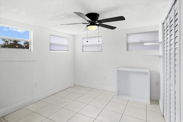 spare room featuring light tile patterned flooring, ceiling fan, a textured ceiling, and baseboards