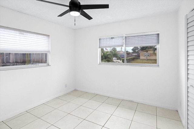 tiled empty room featuring ceiling fan and a textured ceiling