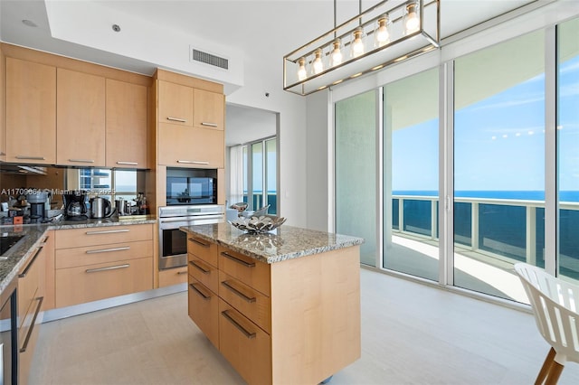 kitchen with a kitchen island, light brown cabinets, oven, and a water view