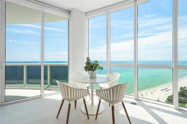 sunroom featuring a water view and a view of the beach