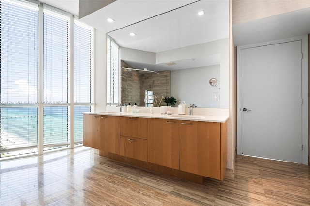 bathroom with vanity, a wall of windows, a shower with shower door, and plenty of natural light