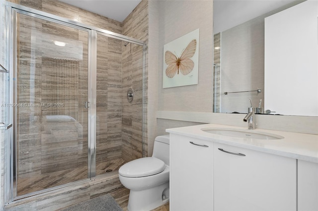 bathroom with a shower with door, vanity, and toilet