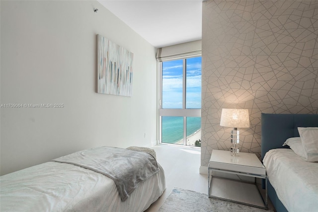 bedroom with multiple windows, a water view, and tile walls