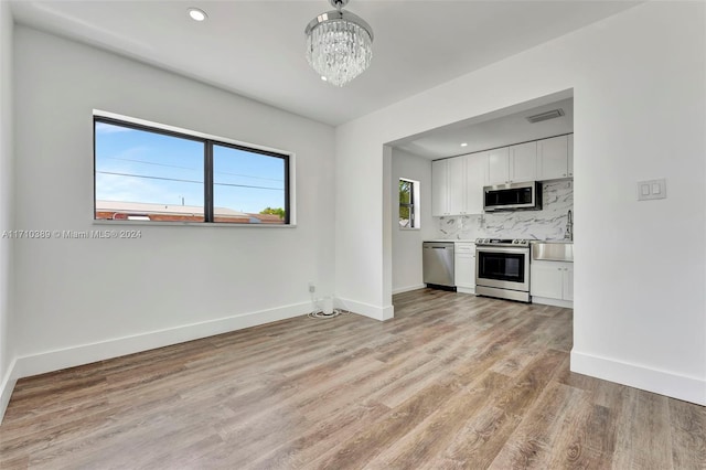 unfurnished living room with light hardwood / wood-style floors and a notable chandelier