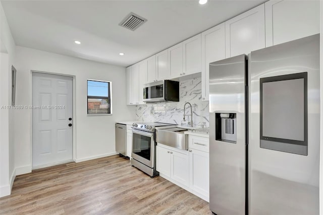 kitchen with decorative backsplash, appliances with stainless steel finishes, light hardwood / wood-style floors, and white cabinetry