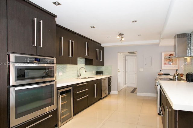 kitchen with sink, wine cooler, backsplash, light tile patterned floors, and appliances with stainless steel finishes