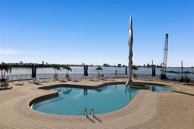 view of swimming pool with a water view, a hot tub, and a patio area