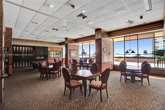 carpeted dining space with a paneled ceiling