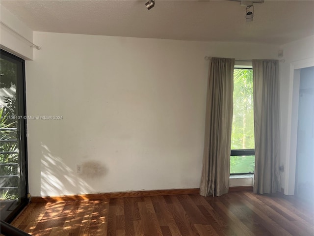 empty room with a textured ceiling and dark wood-type flooring