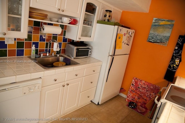 kitchen featuring tile countertops, white appliances, backsplash, white cabinets, and sink