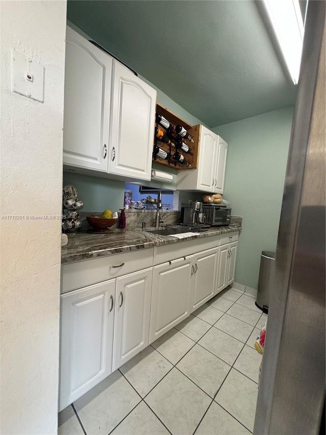 kitchen featuring white cabinetry, sink, and light tile patterned floors