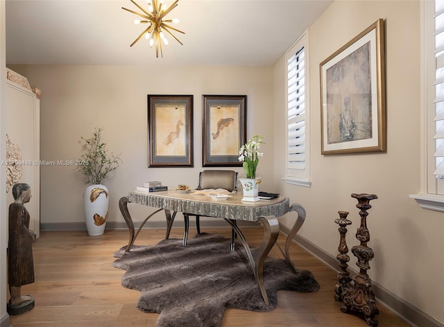 office area with light hardwood / wood-style floors and a notable chandelier