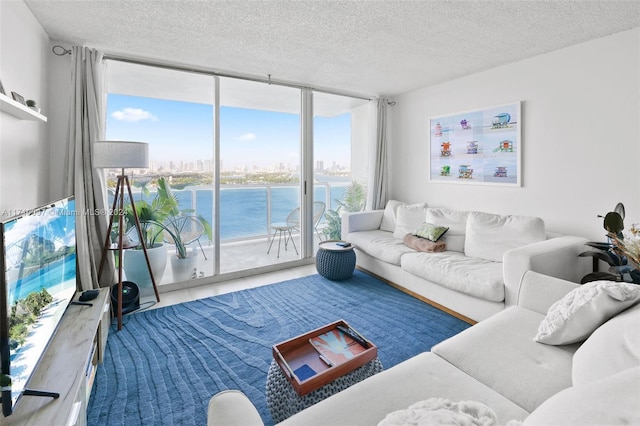 living room featuring a textured ceiling, a water view, and floor to ceiling windows