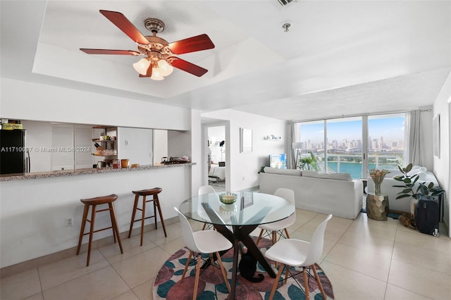 tiled dining area featuring ceiling fan and a tray ceiling