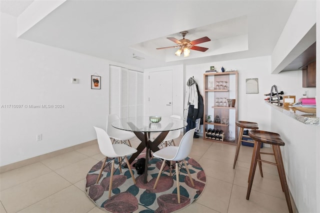 dining space featuring ceiling fan, light tile patterned floors, and a tray ceiling