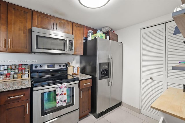 kitchen featuring light stone counters, light tile patterned flooring, and appliances with stainless steel finishes