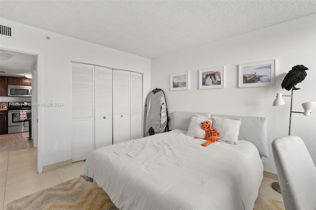 bedroom featuring a textured ceiling, a closet, and light tile patterned flooring