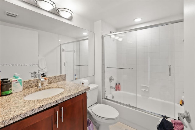 full bathroom featuring combined bath / shower with glass door, tile patterned floors, vanity, and toilet