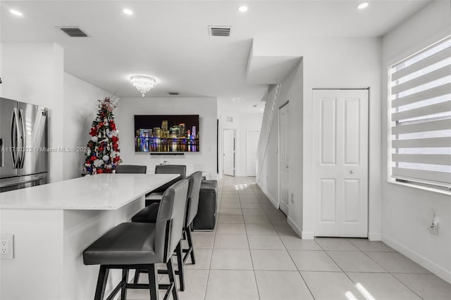 kitchen featuring a kitchen breakfast bar, a center island, light tile patterned floors, and stainless steel refrigerator