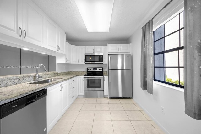 kitchen with white cabinets, appliances with stainless steel finishes, light tile patterned floors, and sink