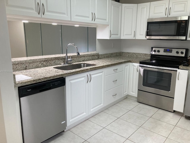 kitchen with light tile patterned flooring, appliances with stainless steel finishes, sink, and white cabinets