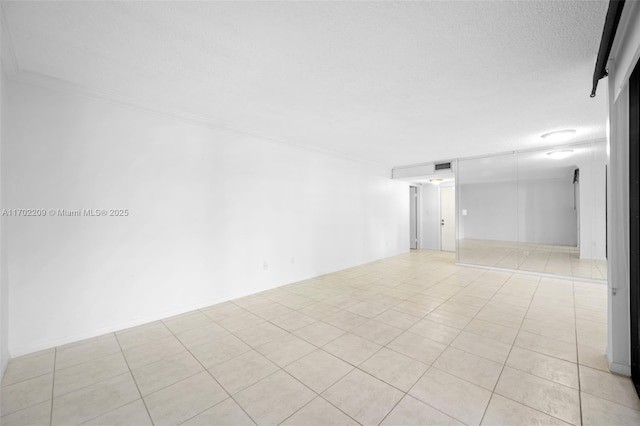 empty room with light tile patterned floors and a textured ceiling