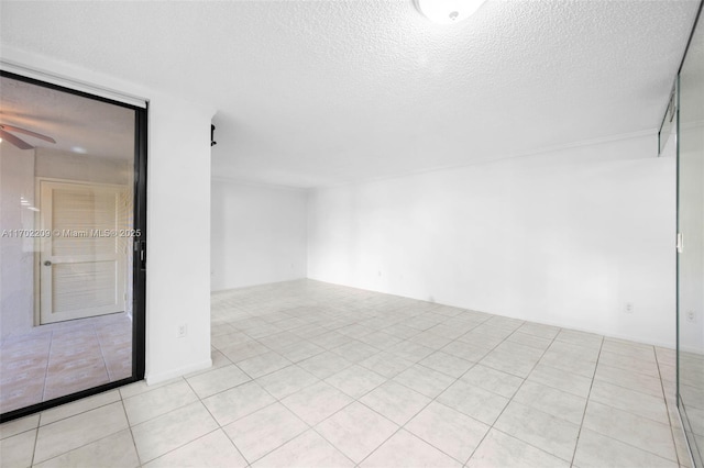 empty room featuring light tile patterned flooring, ceiling fan, and a textured ceiling