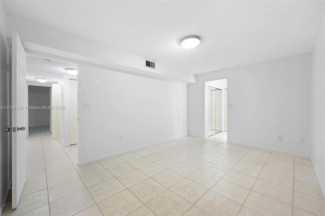 tiled empty room with a textured ceiling