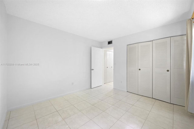 unfurnished bedroom with light tile patterned floors, a closet, and a textured ceiling