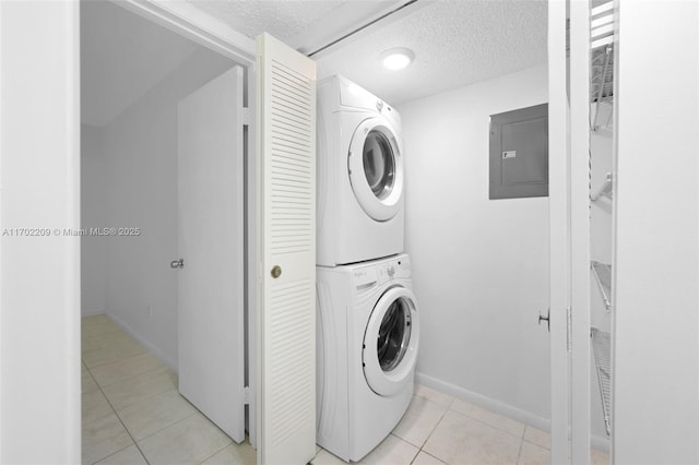 laundry area with stacked washer / dryer, electric panel, a textured ceiling, and light tile patterned floors