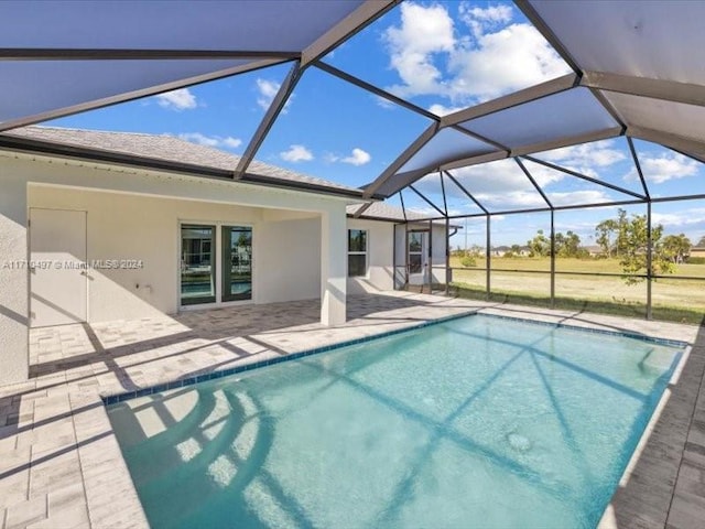 view of pool with glass enclosure and a patio area