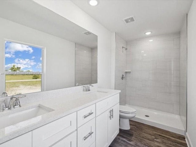 bathroom featuring tiled shower, hardwood / wood-style floors, vanity, and toilet