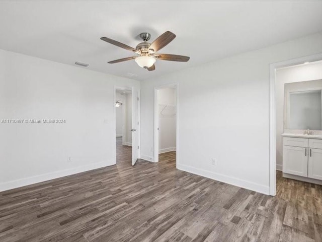 unfurnished bedroom featuring a walk in closet, ceiling fan, dark hardwood / wood-style flooring, and ensuite bathroom