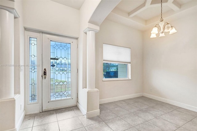 tiled entryway featuring decorative columns, an inviting chandelier, and coffered ceiling