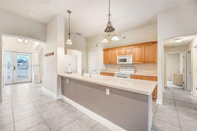 kitchen featuring white appliances, hanging light fixtures, sink, kitchen peninsula, and light tile patterned flooring