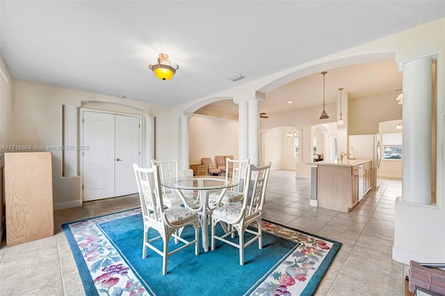 dining room with sink, decorative columns, and light tile patterned floors