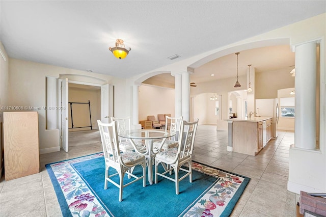 tiled dining space featuring decorative columns and sink