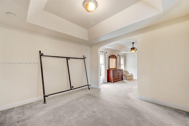 spare room featuring ceiling fan, light carpet, and a tray ceiling