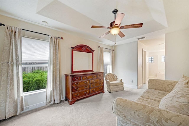 living area featuring light carpet, ceiling fan, a wealth of natural light, and a raised ceiling