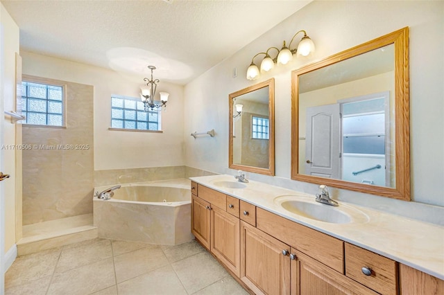 bathroom featuring a textured ceiling, tile patterned flooring, a tub to relax in, and vanity