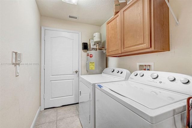 laundry room featuring washer and dryer, a textured ceiling, cabinets, electric water heater, and light tile patterned floors