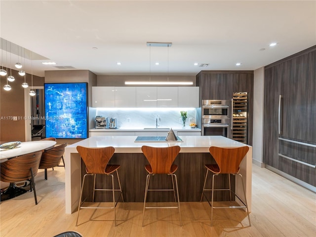 kitchen featuring white cabinetry, a kitchen island, stainless steel double oven, and light wood-type flooring