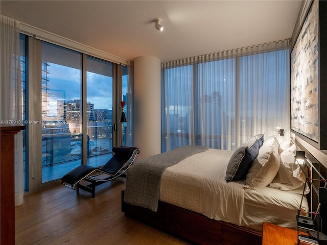 bedroom featuring access to outside, floor to ceiling windows, and hardwood / wood-style flooring