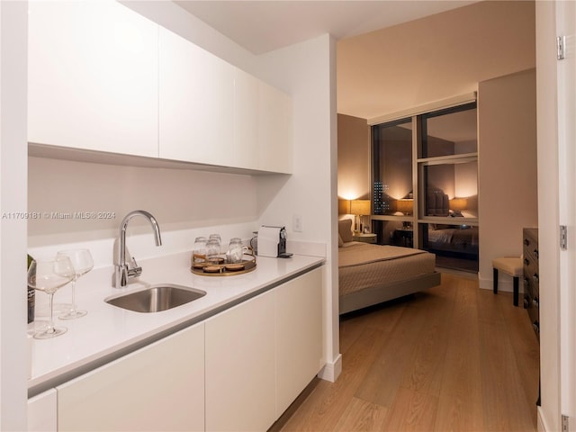 interior space with white cabinetry, sink, and light hardwood / wood-style floors