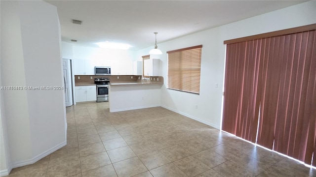 kitchen with tasteful backsplash, kitchen peninsula, decorative light fixtures, white cabinets, and appliances with stainless steel finishes