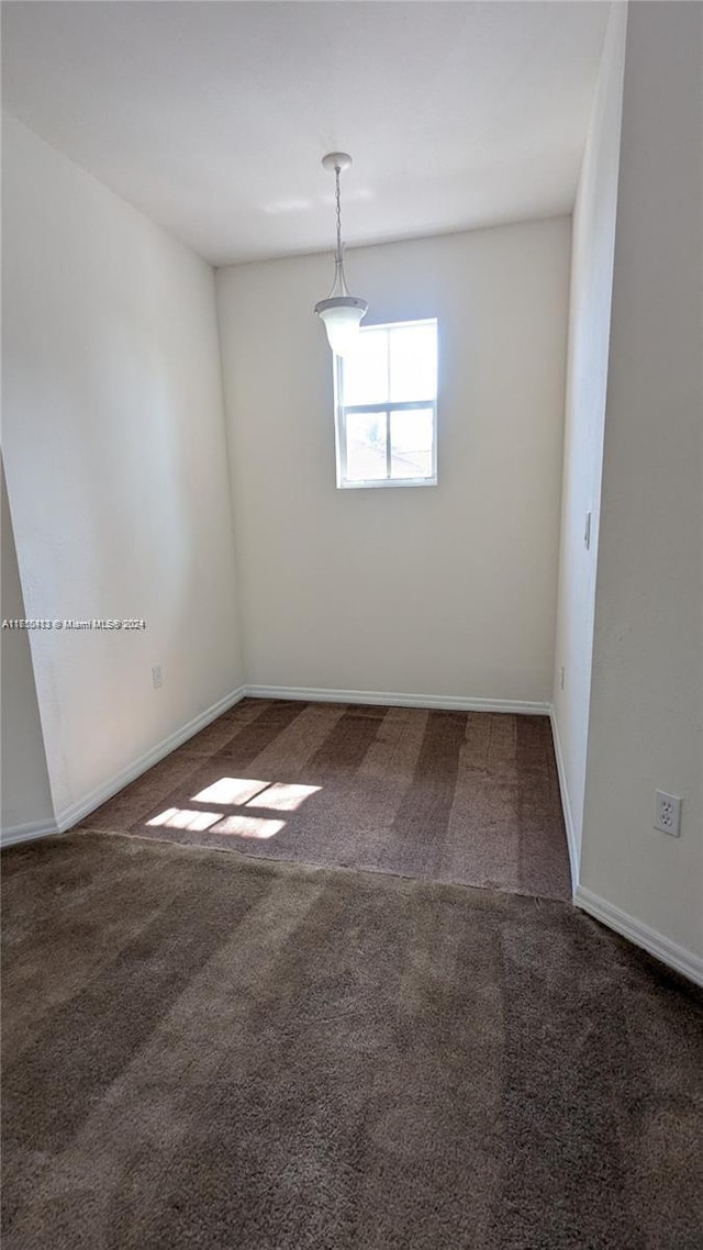 unfurnished room with dark colored carpet