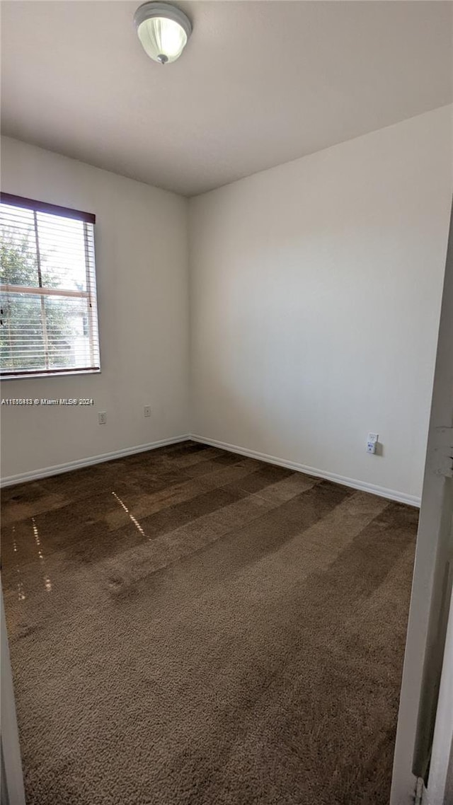 unfurnished room featuring dark colored carpet