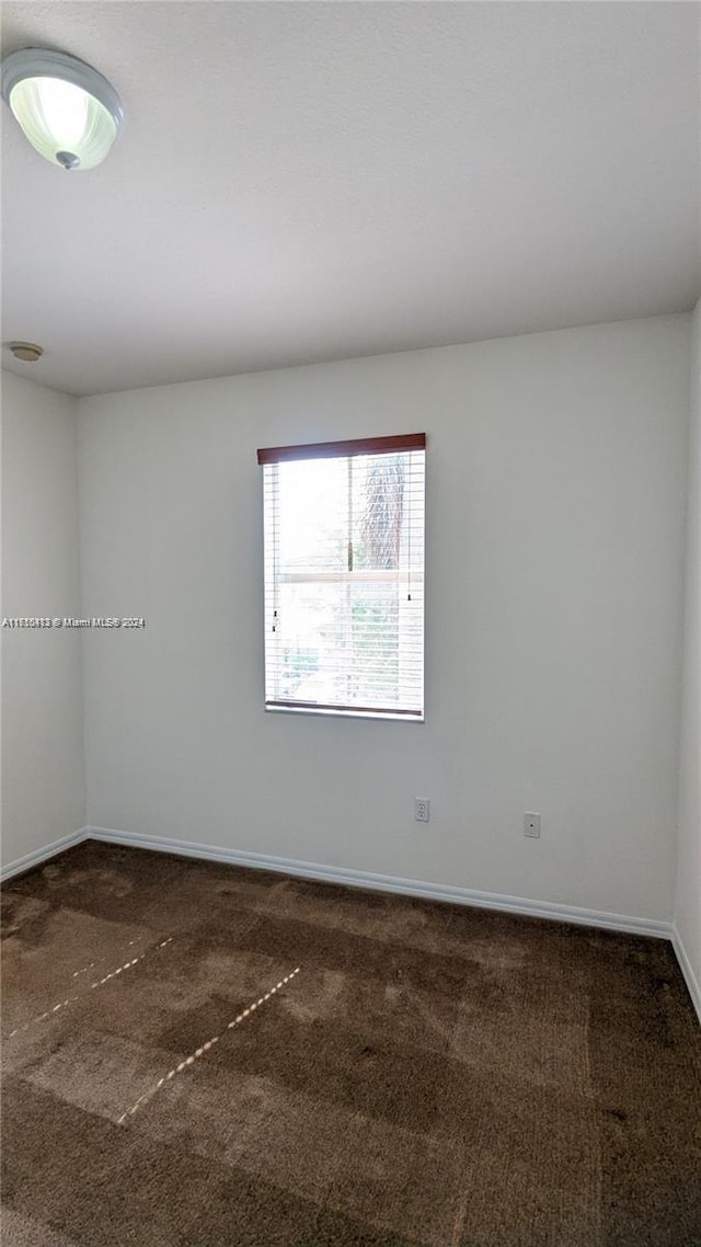 unfurnished room featuring dark colored carpet